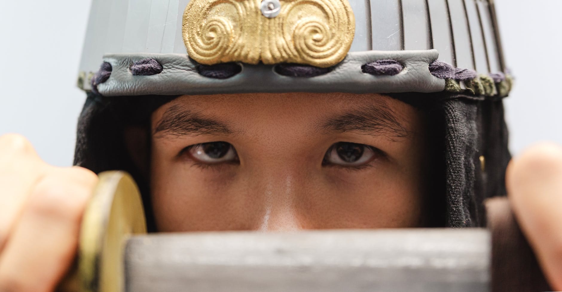 Zbliżenie oczu samuraja w hełmie, z uniesionym mieczem