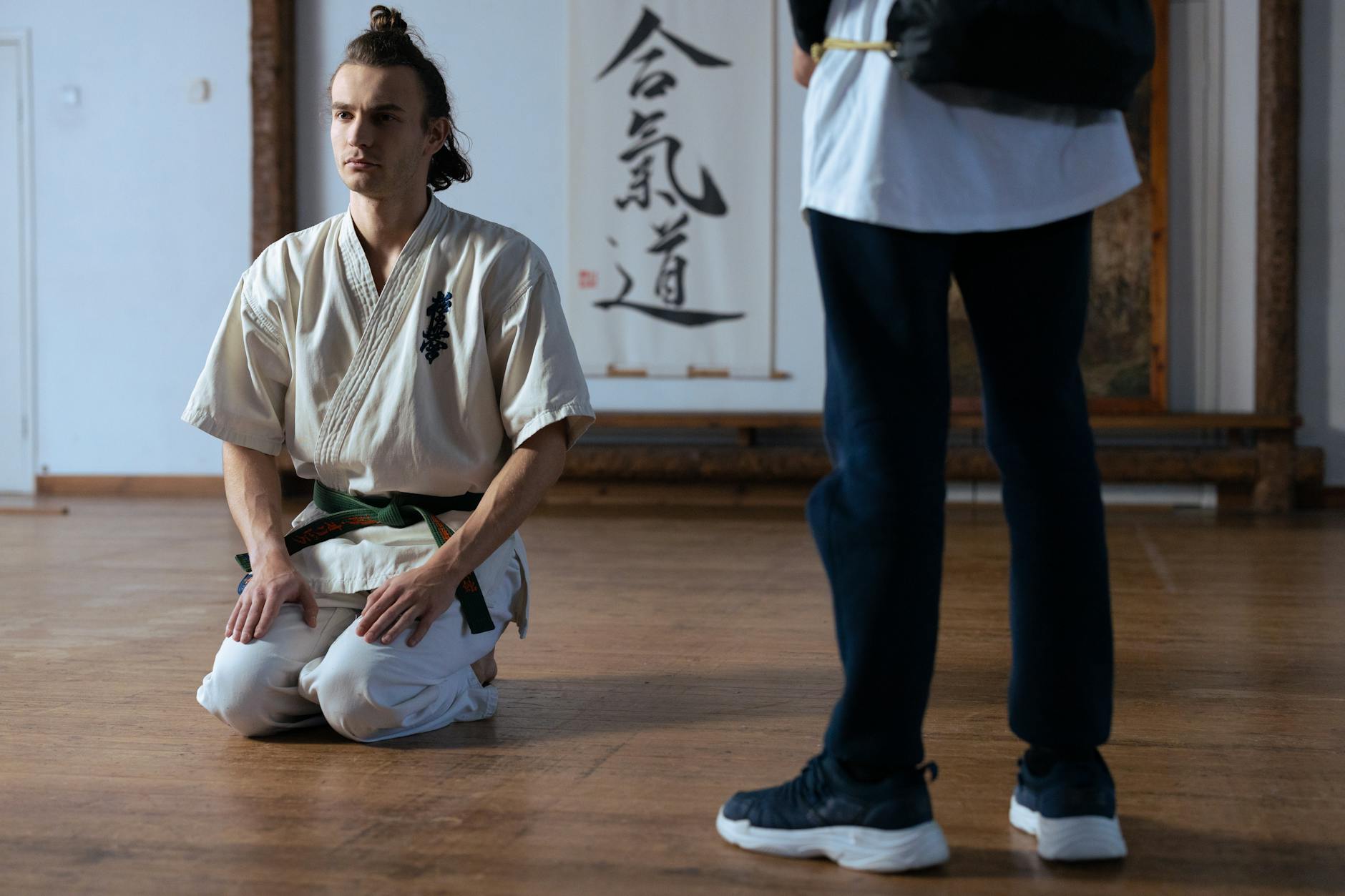 Adept aikido w tradycyjnym stroju klęczy w dojo, skupiony na oddechu