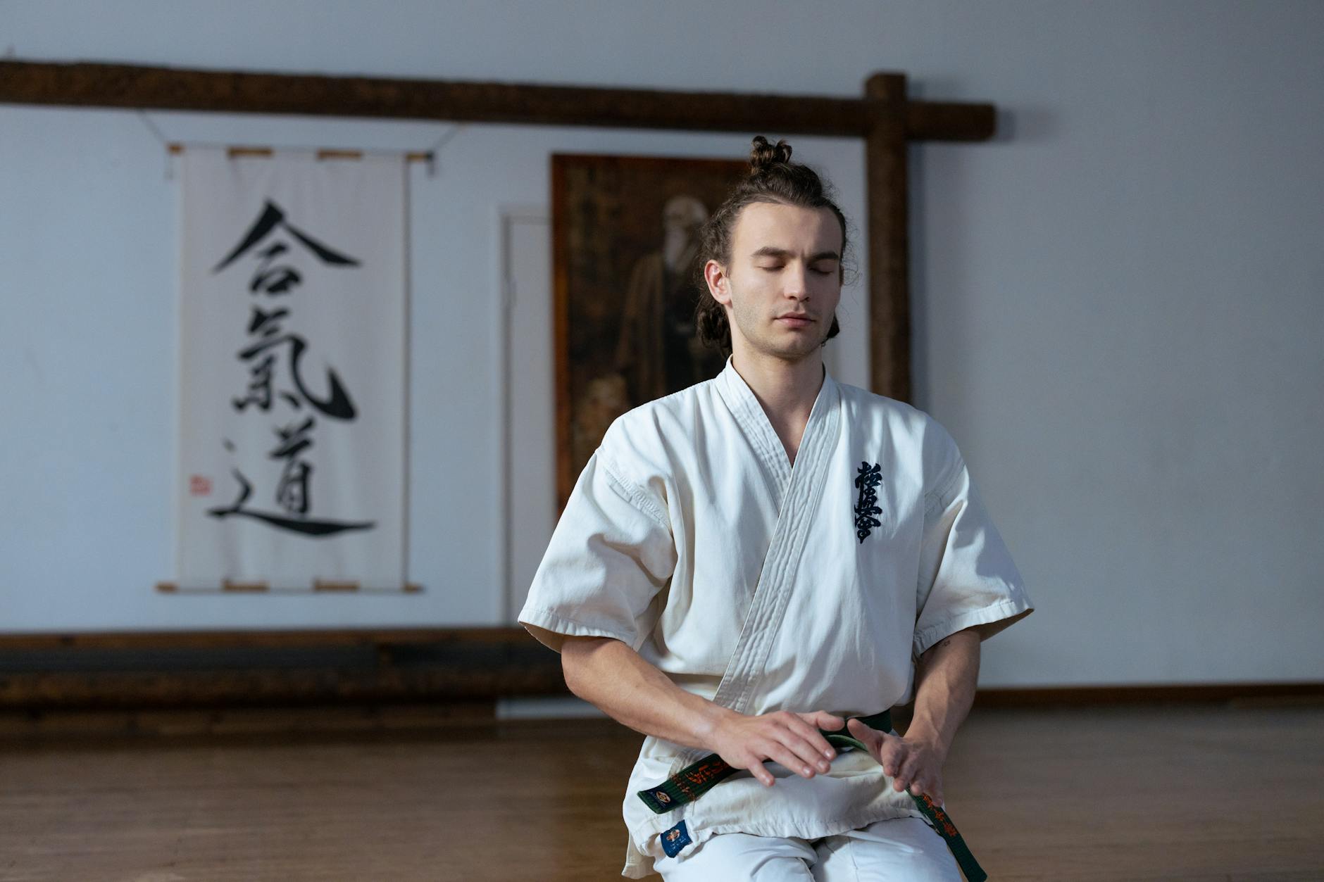 Adepta aikido w kimonie medytuje na macie dojo, skupiony na oddechu