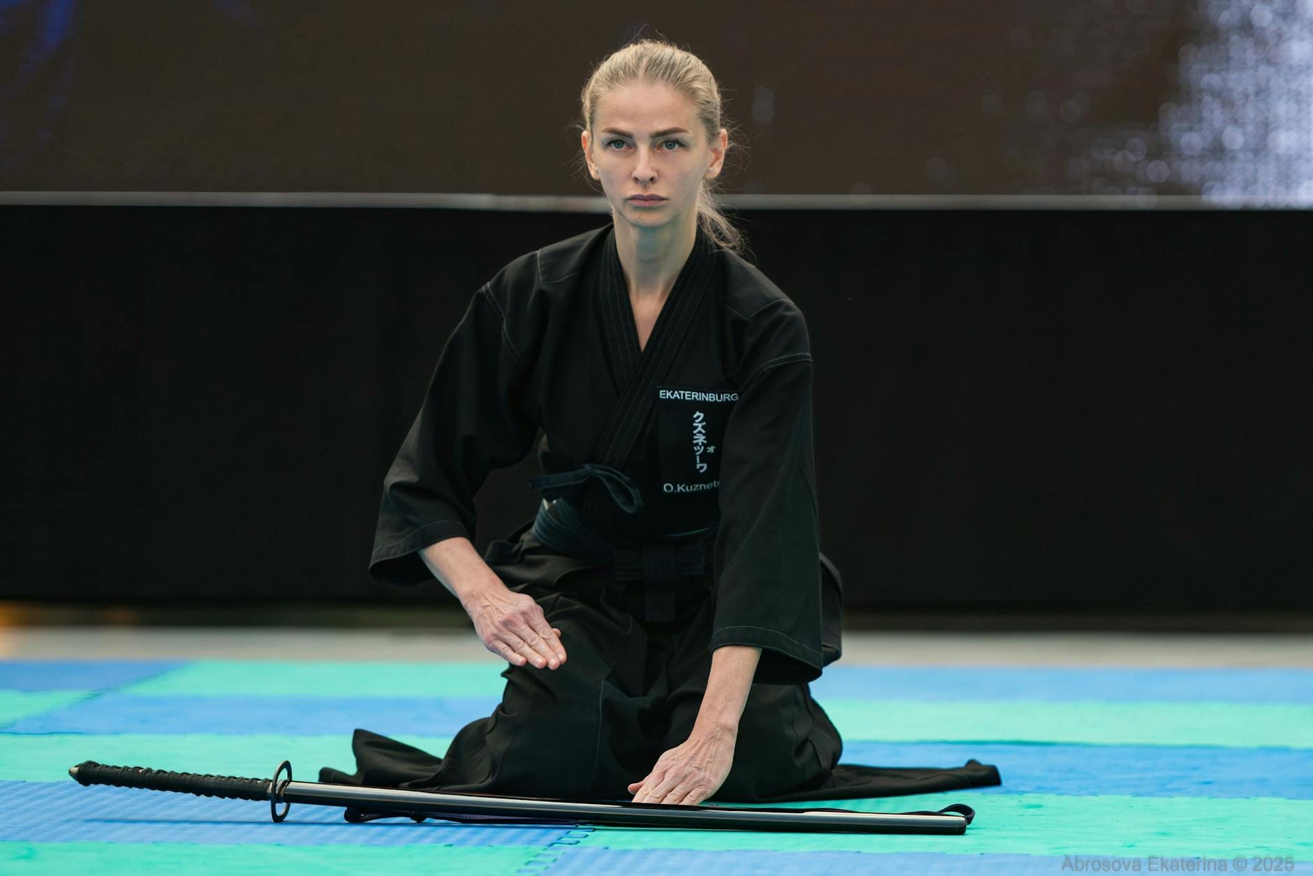 Samuraj w czarnym gi ćwiczy iaido z mieczem w dojo