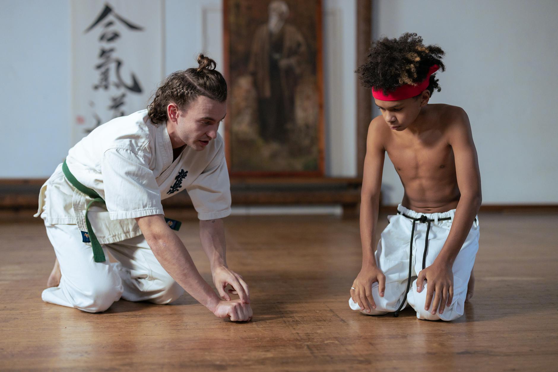 Instruktor karate uczy młodego ucznia poprawnej postawy w dojo