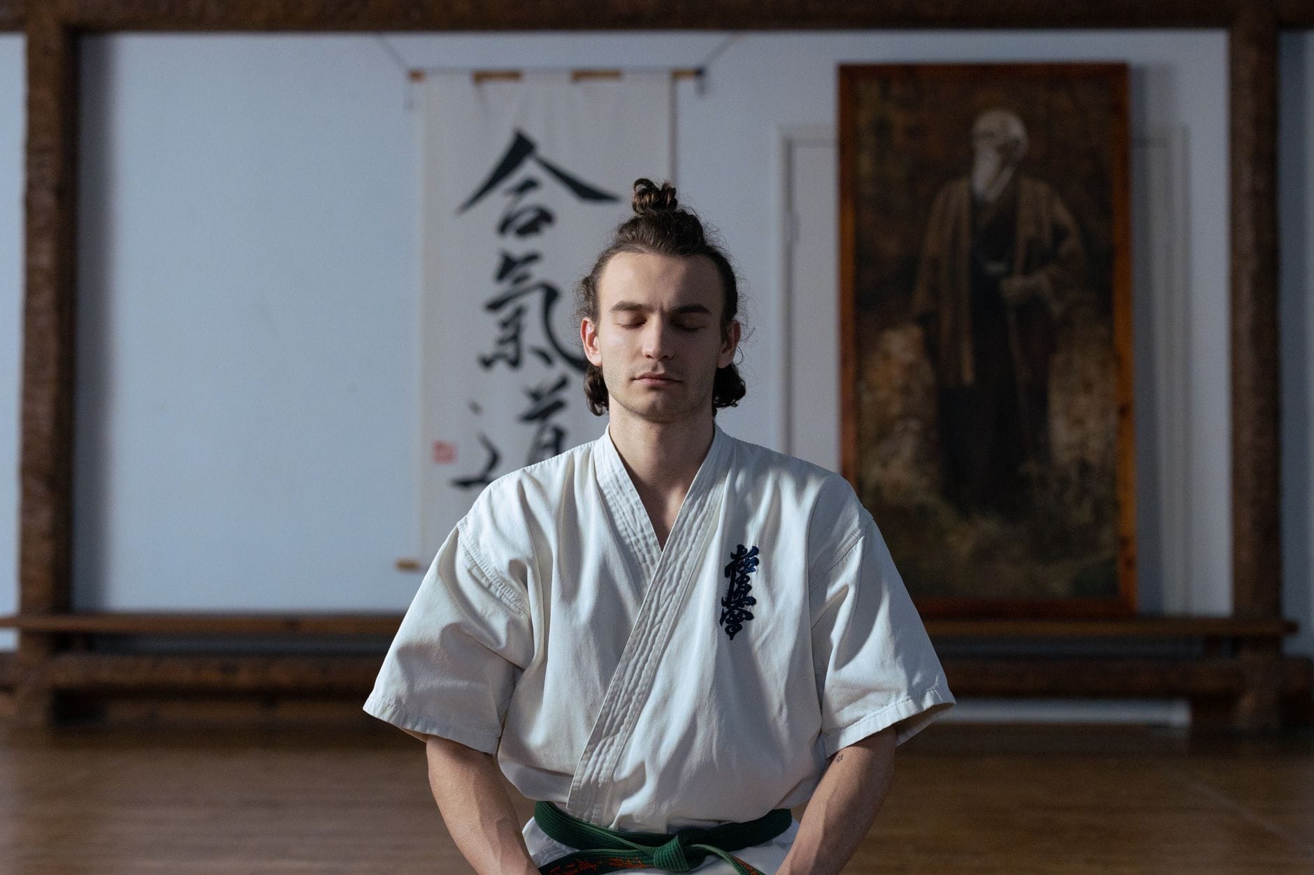 Budoka medytuje z zamkniętymi oczami w spokojnym dojo