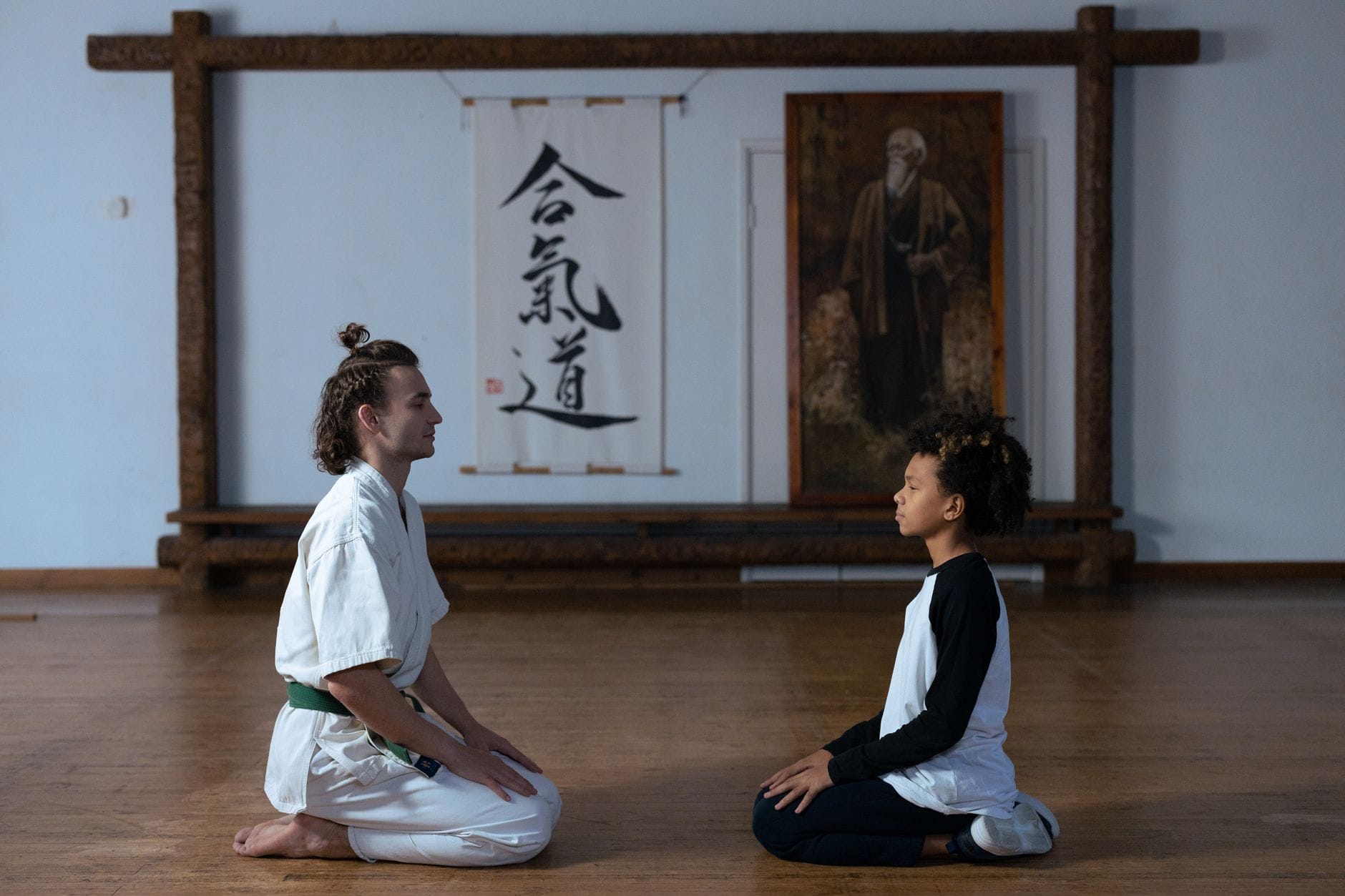 Sensei i dziecko medytują w dojo na drewnianej podłodze