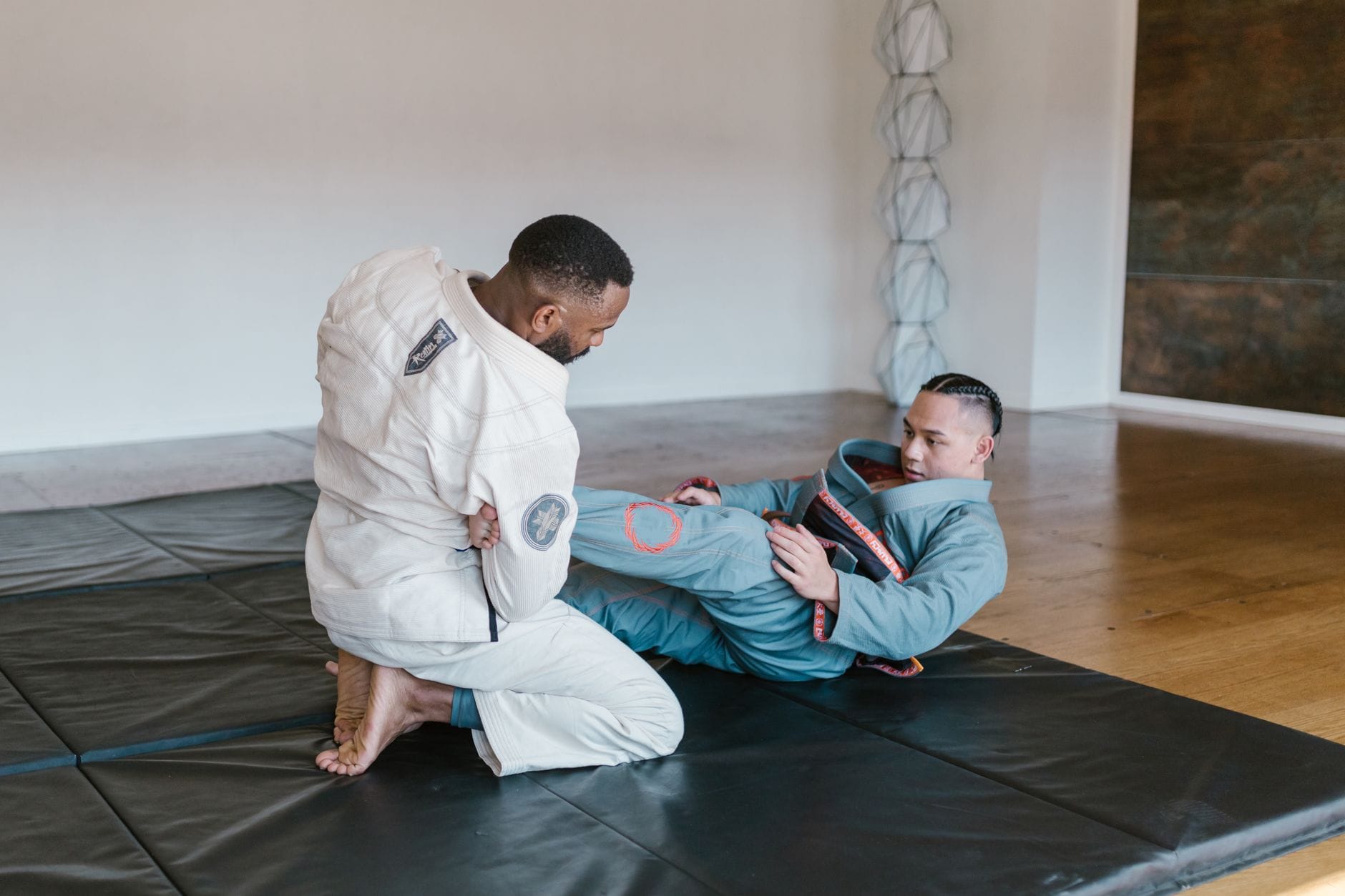 Filozofia „ustąp, aby zwyciężyć” w jujutsu a współczesne pojęcie asertywności i stawiania granic Dwóch mężczyzn trenuje brazylijskie jiu-jitsu na macie w sali treningowej